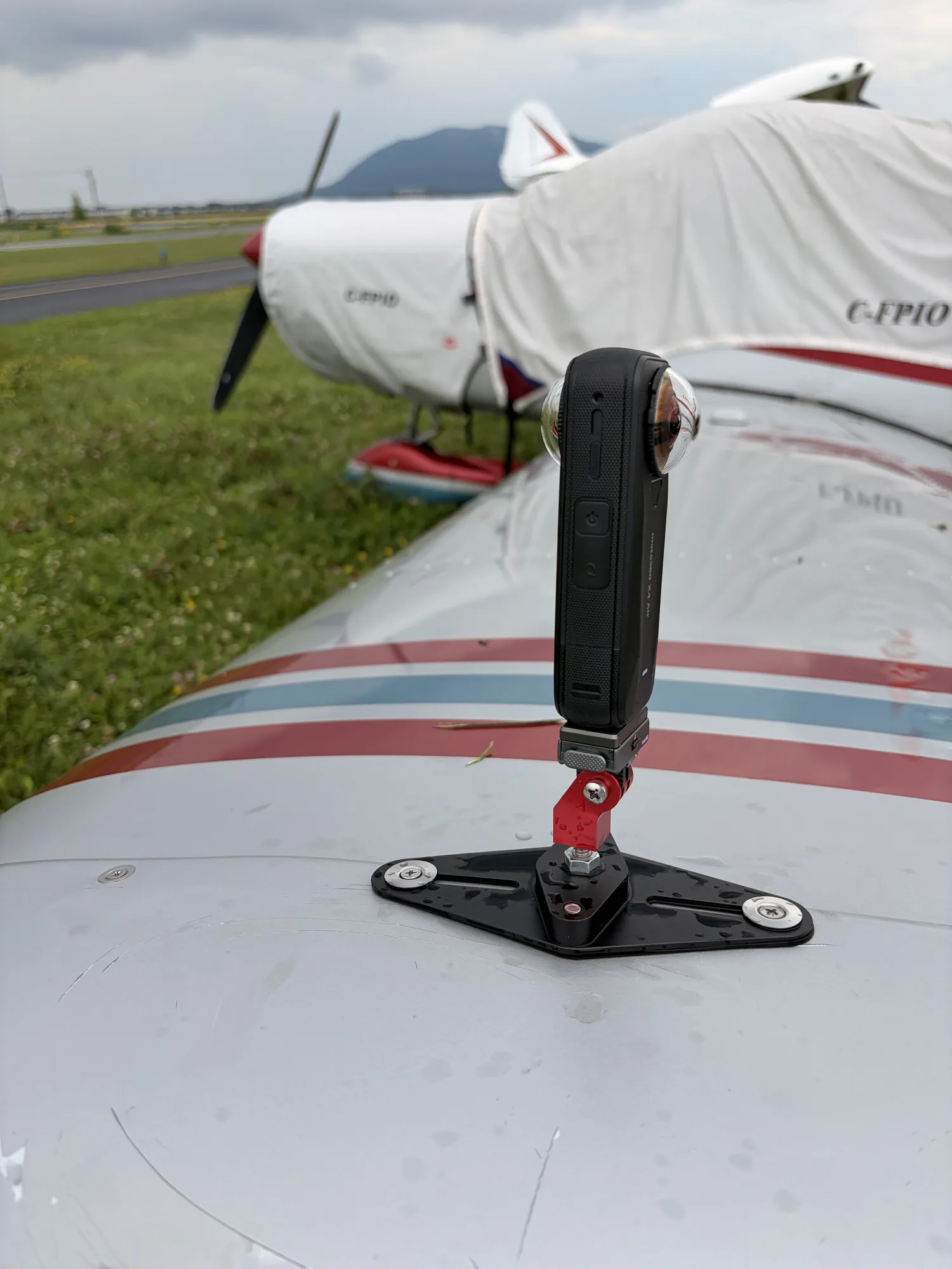 A 360 camera hard-mounted to the wing of C-FPIO, the Piper Cherokee testbed, at a grass tiedown